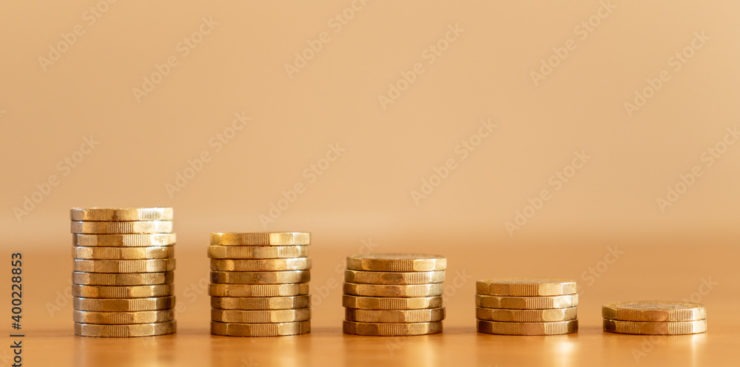 Close up of stacks of many GBP one pound coins decreasing in size as money going down symbolising the effects of inflation, UK